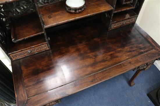 A late 19th century/early 20th century carved Chinese hardwood desk, carved in the round with bamboo flowers and foliage with possibly